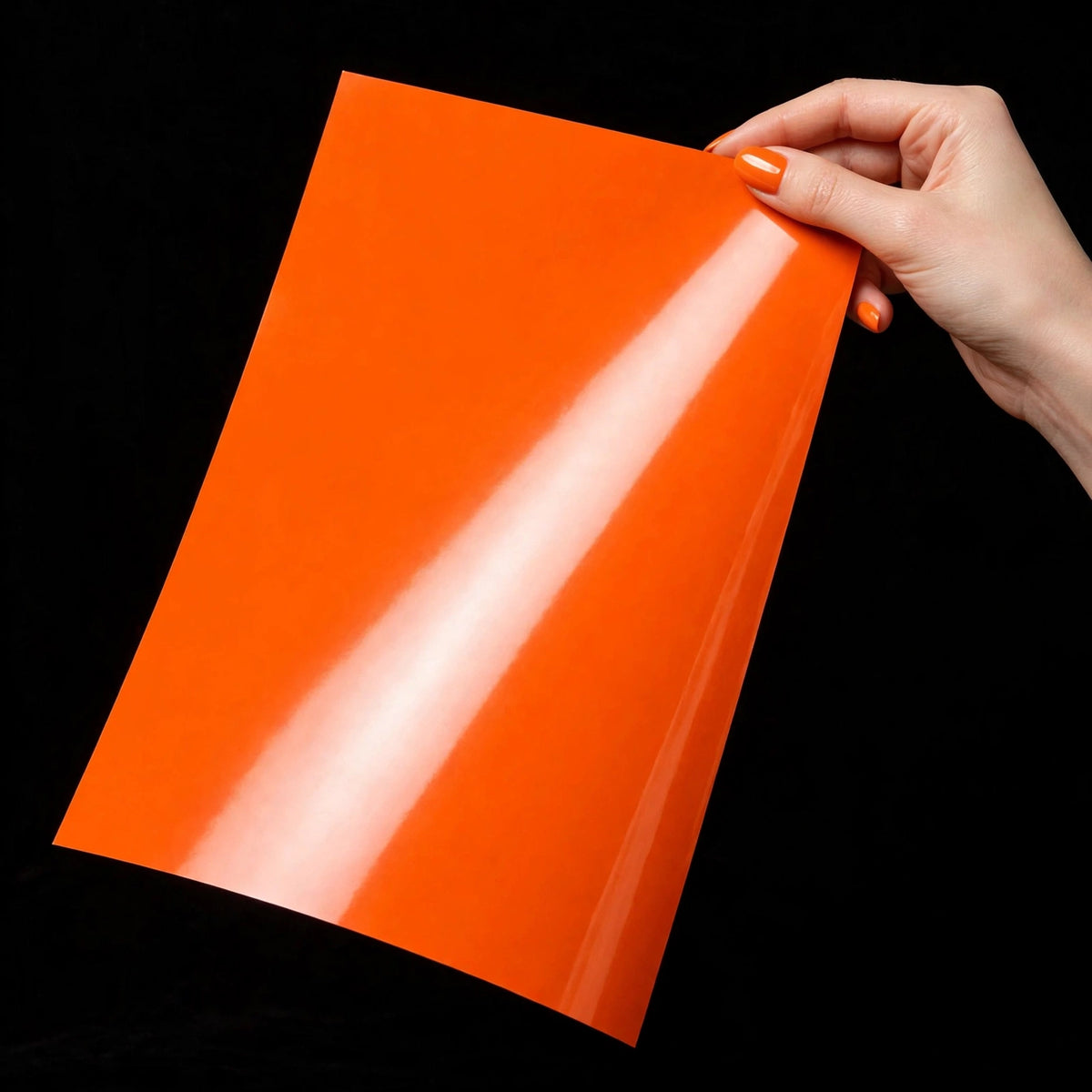 Super Gloss Hermes Orange vinyl wrap film sheet held in hand
